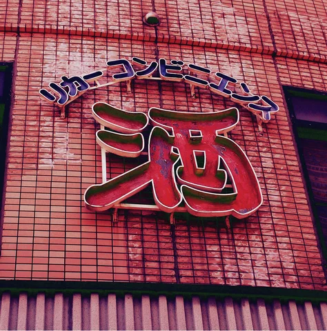 A large red outlined character sign is mounted on a red tiled facade.
