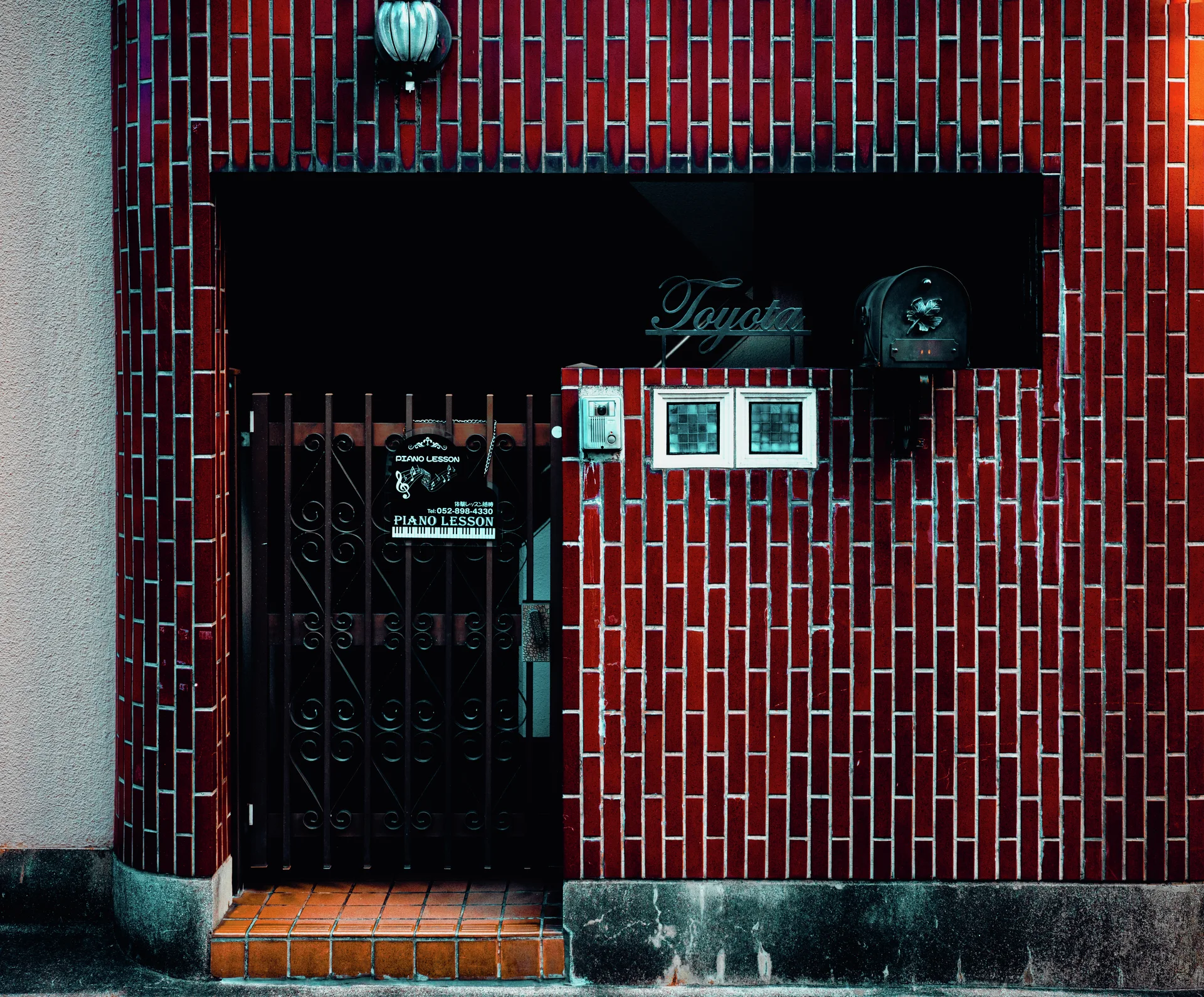 A dark recessed doorway and small display panels interrupt a wall covered in narrow red tiles.