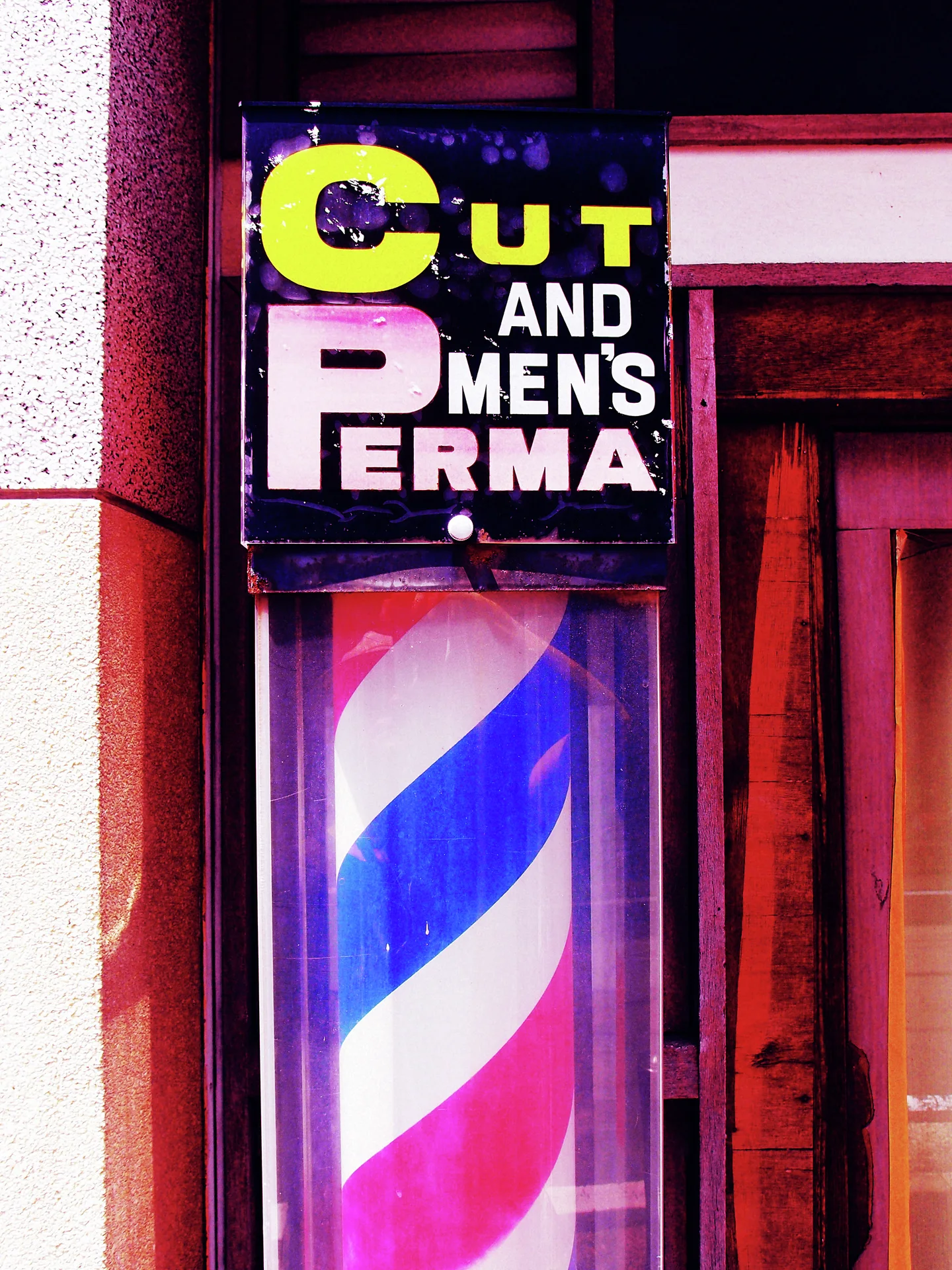 A red, white, and blue barber pole sits beneath bold haircut lettering.