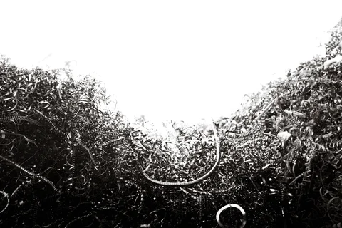 Dense tangled metal shavings surround a bright opening, with curled strands visible in black and white.