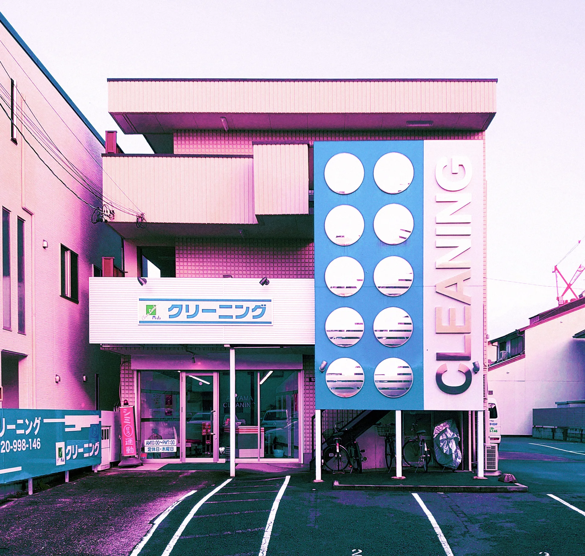 A pink cleaning shop has a tall blue panel punctuated by ten circular openings.