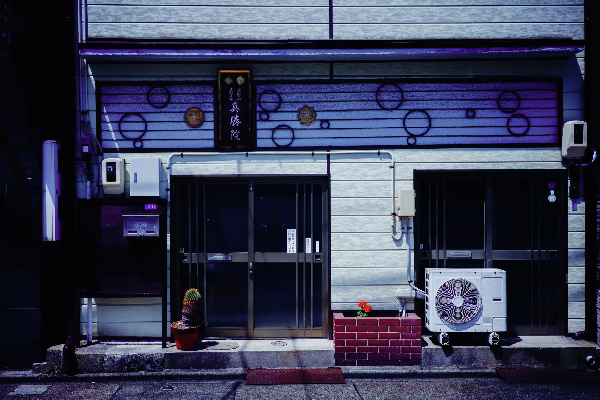 Circular decorations cover a blue-toned facade above glass doors and an outdoor air conditioner.