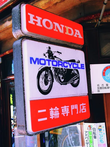 A projecting Honda motorcycle sign combines red panels, blue lettering, and a black illustrated motorcycle.