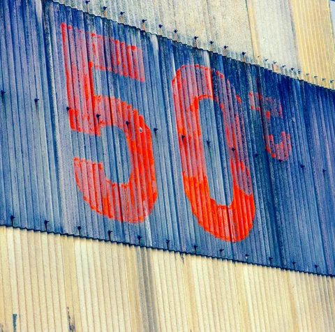 Faded red number 50 spans a dark blue stripe across pale corrugated metal siding.