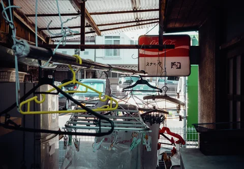 Empty plastic clothes hangers crowd a covered passage beneath a red and white Coca-Cola sign.