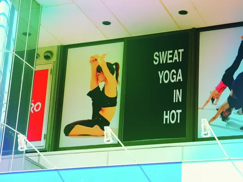 A yoga advertisement shows a woman stretching beside stacked white lettering on a dark green panel.