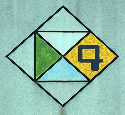 A diamond wall emblem contains green and blue triangles beside a dark numeral four on yellow mosaic.