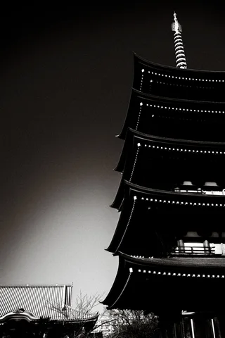 A black-and-white pagoda rises against an open sky, its curved roof tiers topped by a ringed spire.