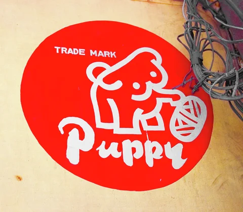 A white cartoon puppy holding yarn appears inside a red circle beside tangled wall cables.