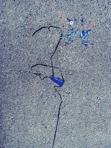 Loose black tape and small blue fragments lie scattered across rough gray pavement.