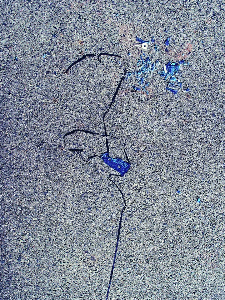 Loose black tape and small blue fragments lie scattered across rough gray pavement.