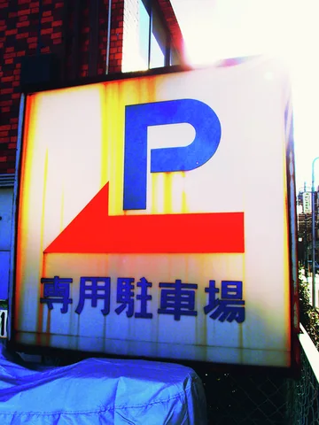 A weather-streaked white parking sign bears a large blue P and red left-pointing arrow.