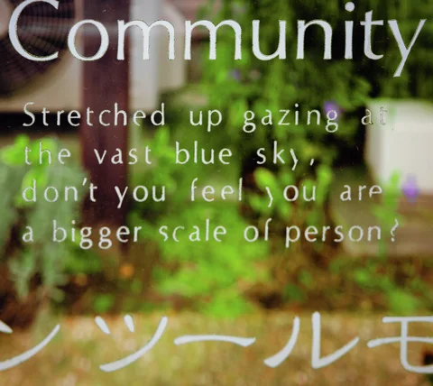 White English and Japanese lettering covers glass reflecting green foliage and a softly blurred building.