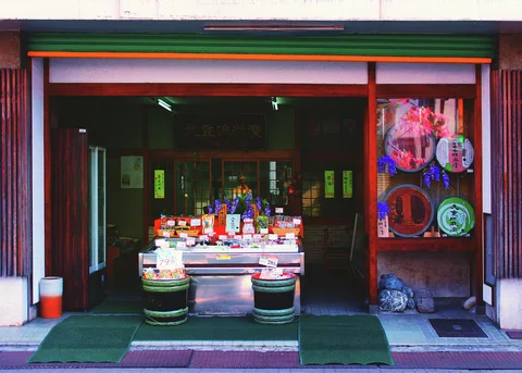 Small goods fill a central display inside a wide shop entrance bordered by two round containers.