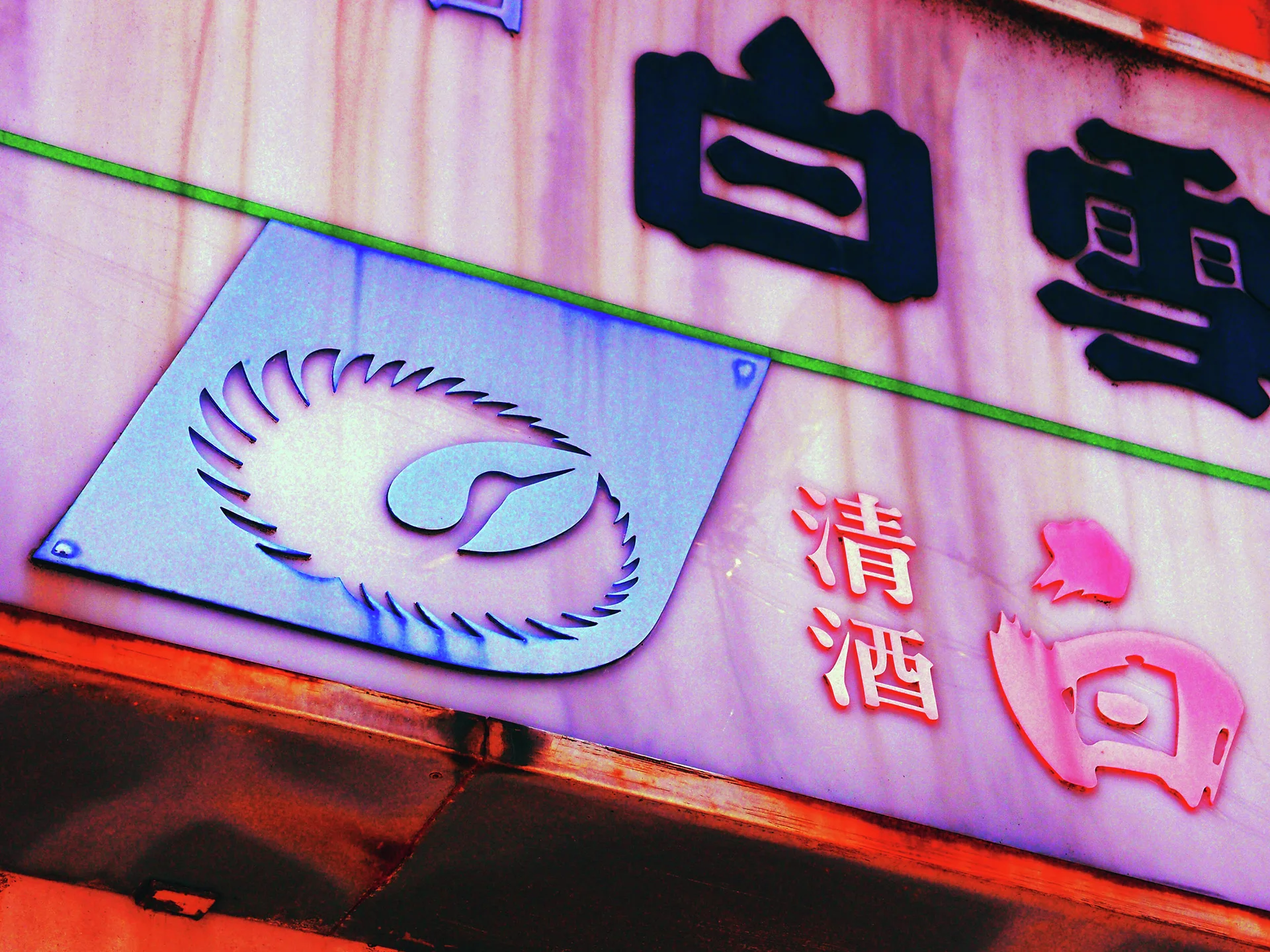Raised dark characters and a metallic circular emblem decorate a pink-toned shop fascia.