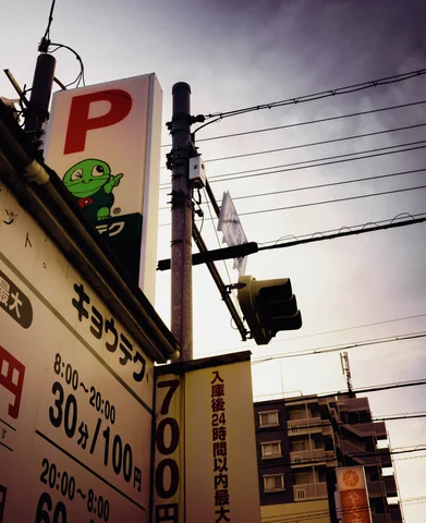 A parking sign with a large red P rises beside utility poles and dense overhead cables.