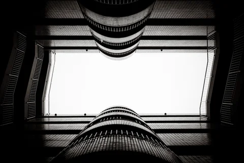 Curved balcony rails frame a bright rectangular opening overhead in a symmetrical black and white view.