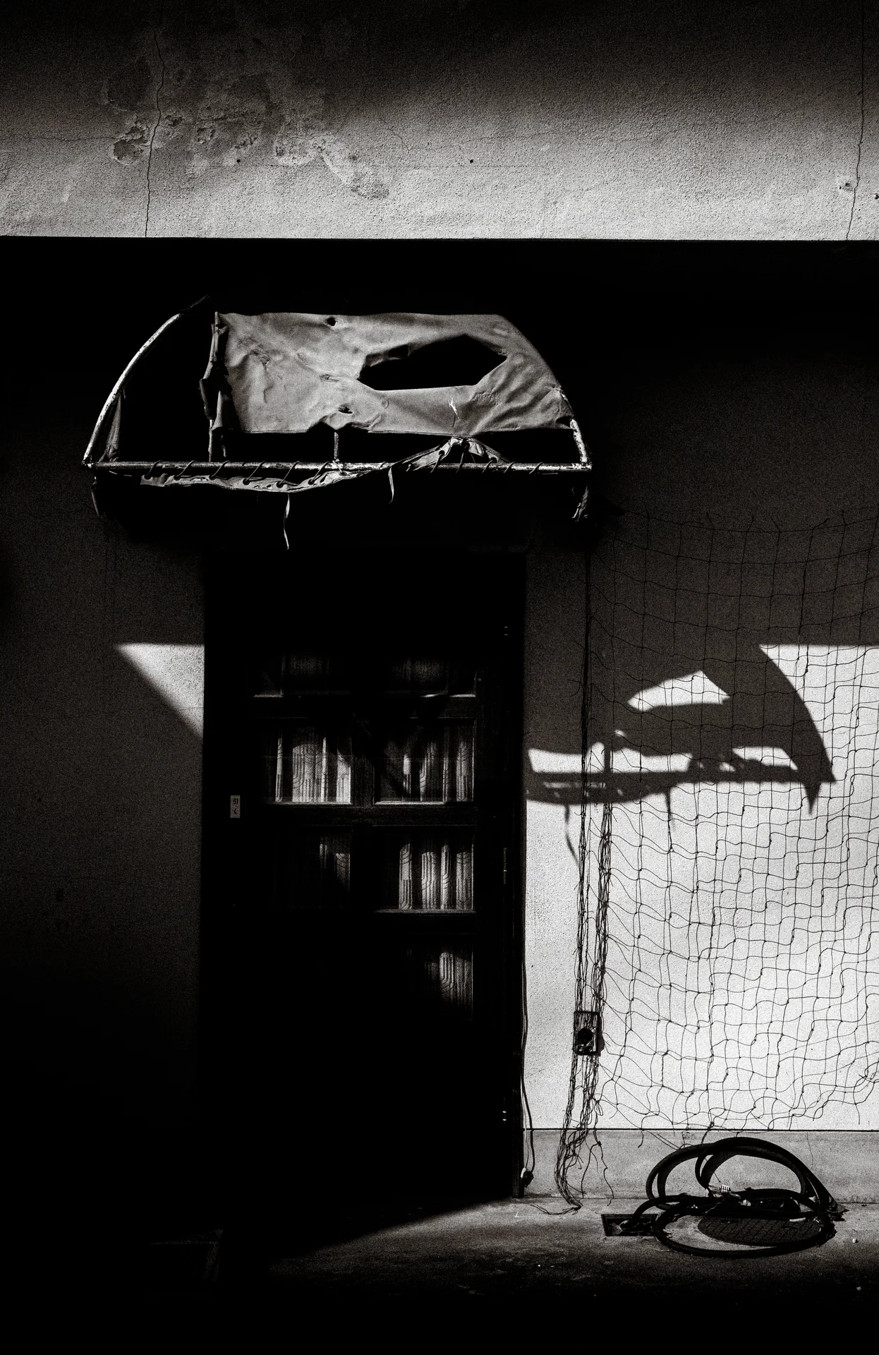 A dark recessed cabinet with a covered top casts an angular wall shadow in black and white.