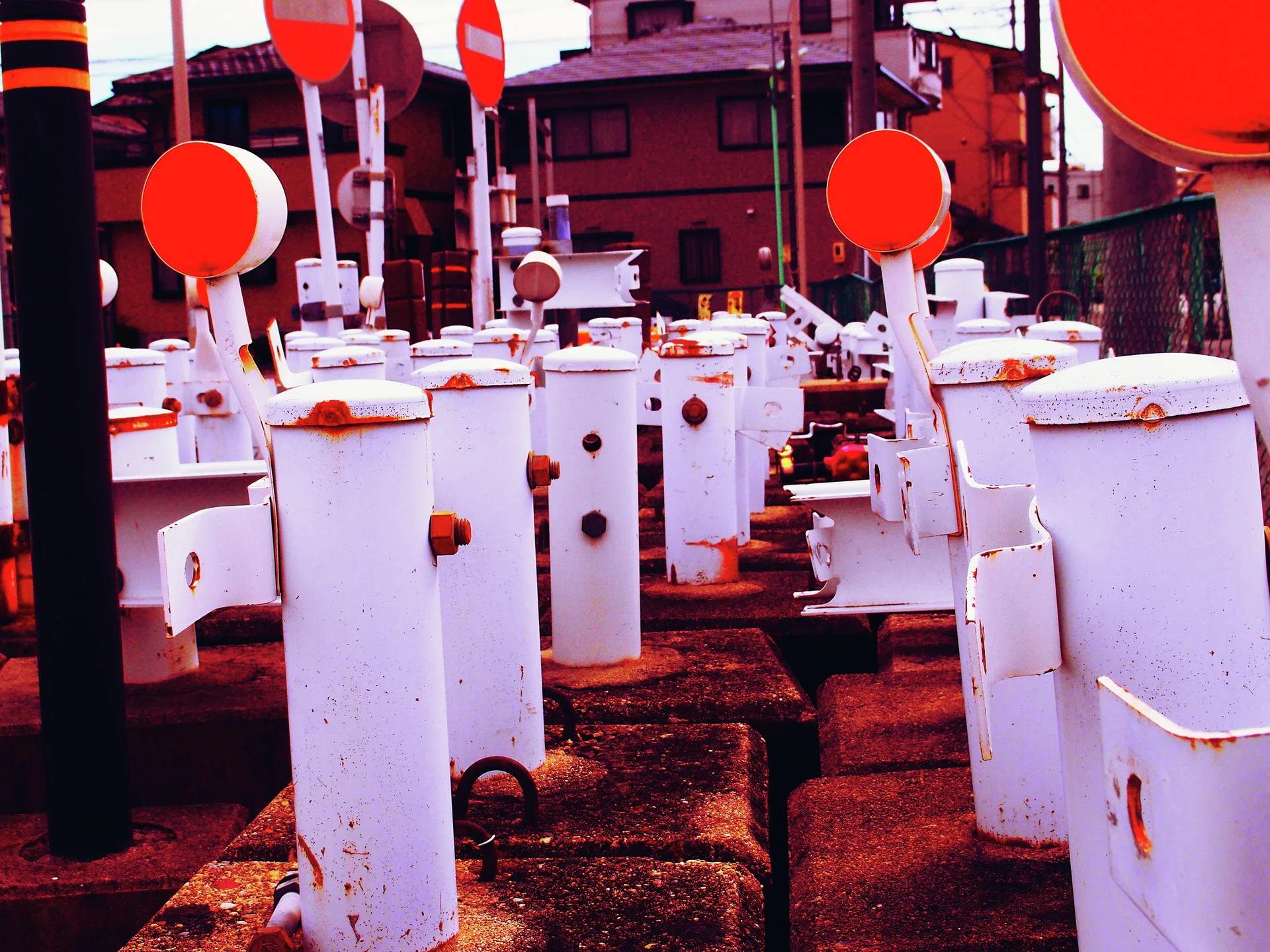 Rows of white railway crossing mechanisms have round orange-red markers on raised arms.