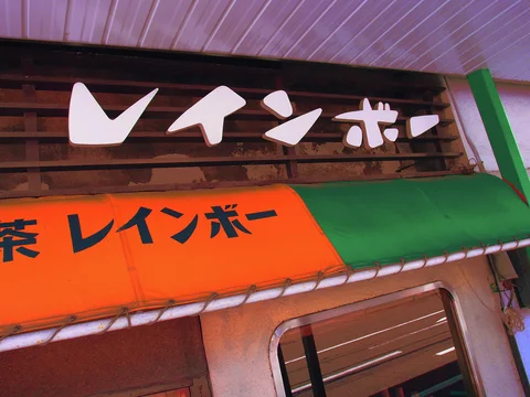 White raised characters top an orange and green awning beneath a pale ceiling.
